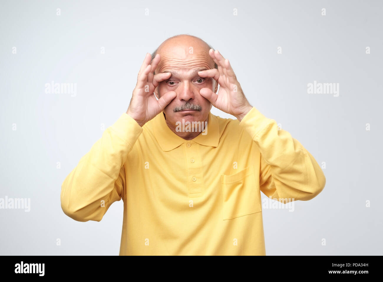 Handsome bored sleepy senior man trying to open his eyes with fingers. Stock Photo