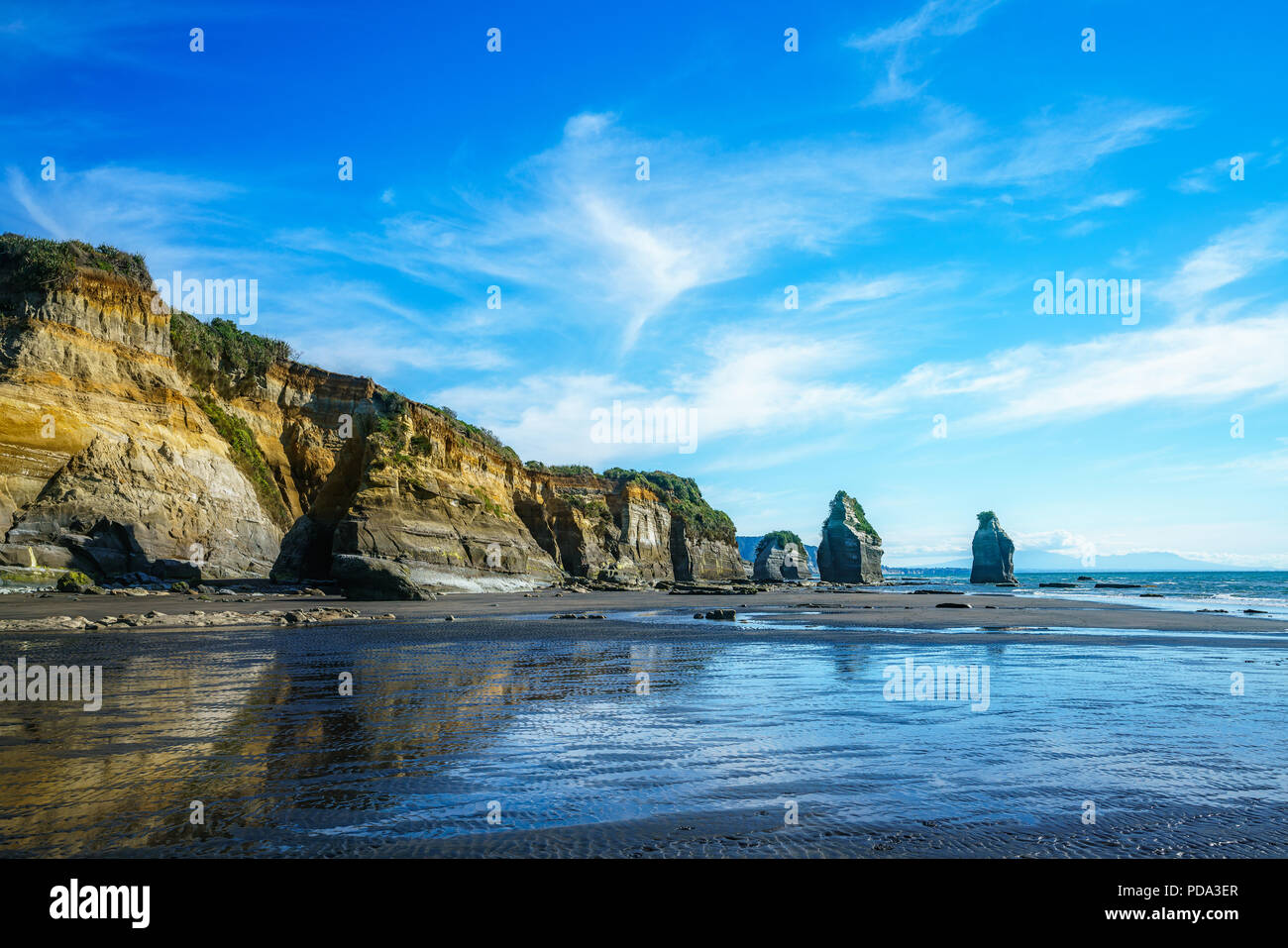 blue water, golden rocks and sand. on the beach, 3 sisters and elephant rock, new zealand Stock Photo