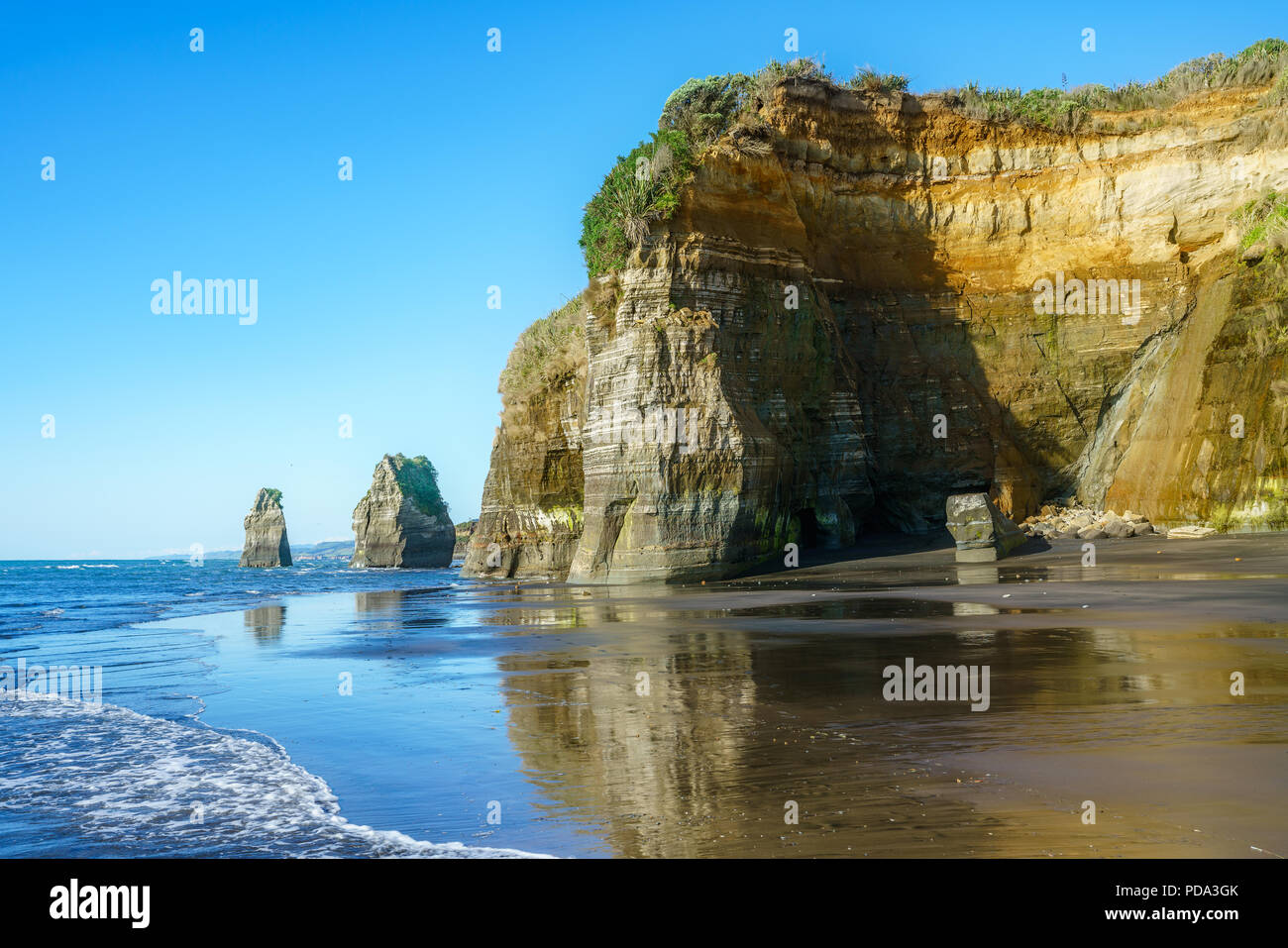 blue water, golden rocks and sand. on the beach, 3 sisters and elephant rock, new zealand Stock Photo