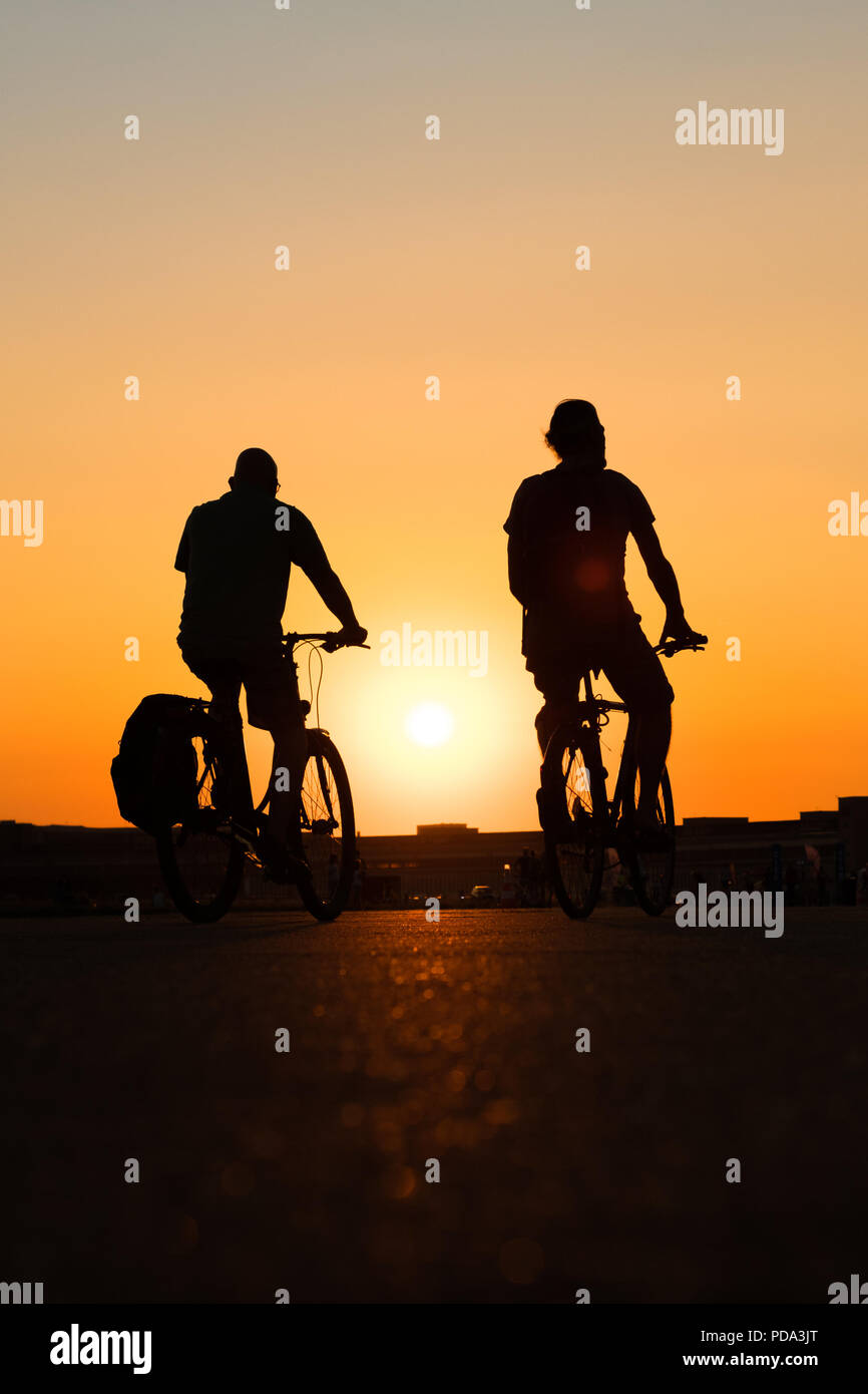 silhouette of a person riding bicycle with sunset sky background Stock Photo