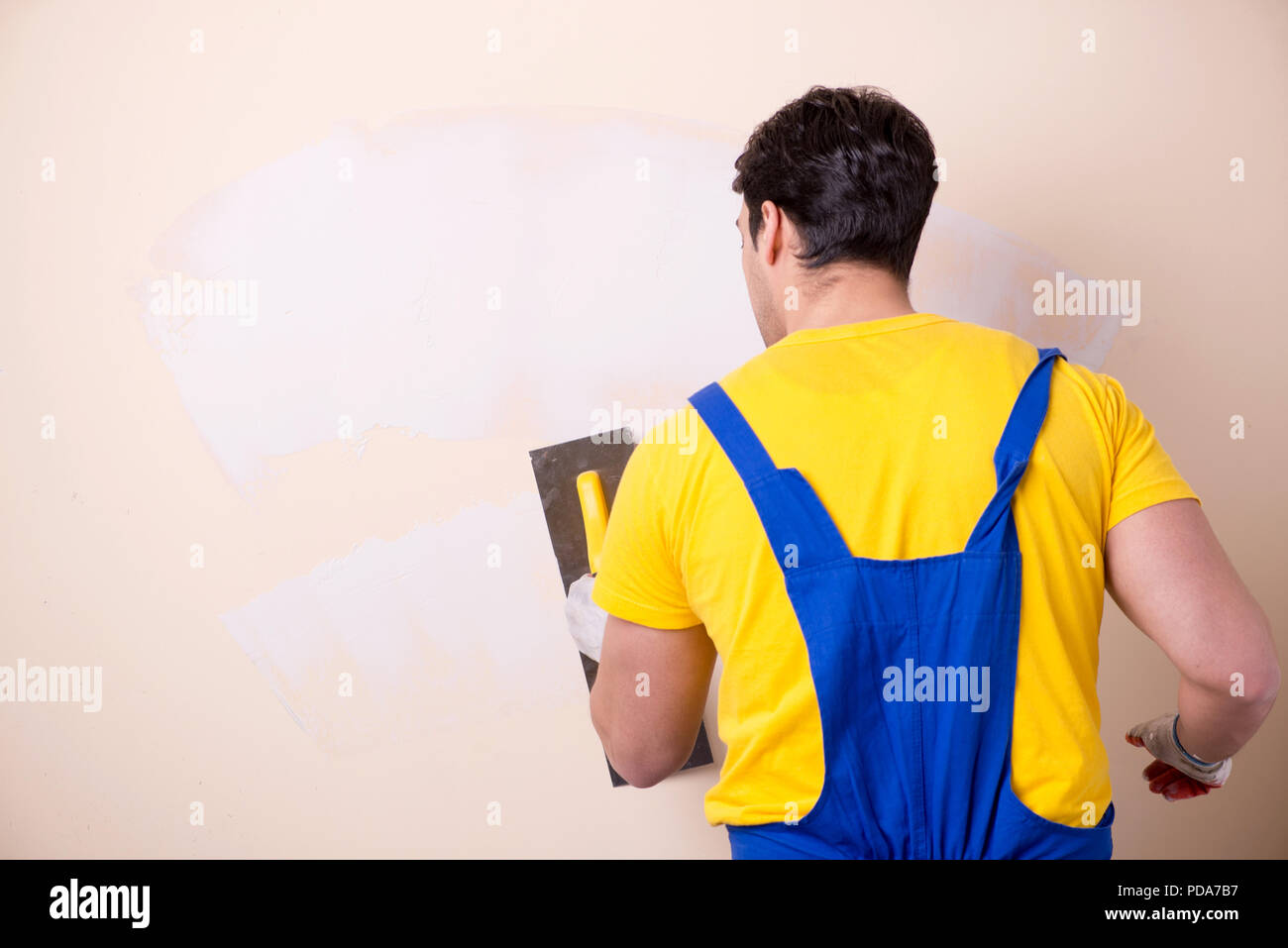 Young contractor employee applying plaster on wall Stock Photo