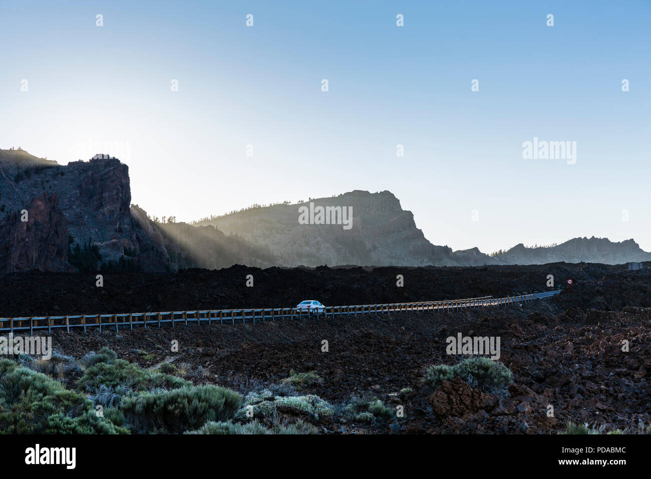 Low sunlight backlighting the barrier fence along the road through the Las Canadas del Teide volcanic landscape, unesco protected world heritage site, Stock Photo