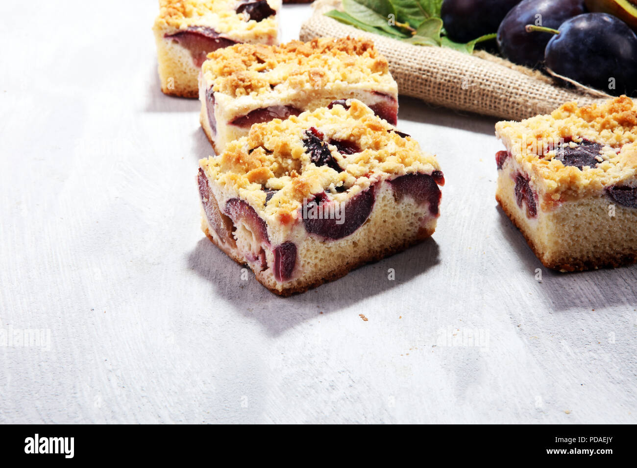 Rustic plum cake on wooden background with plums around Stock Photo