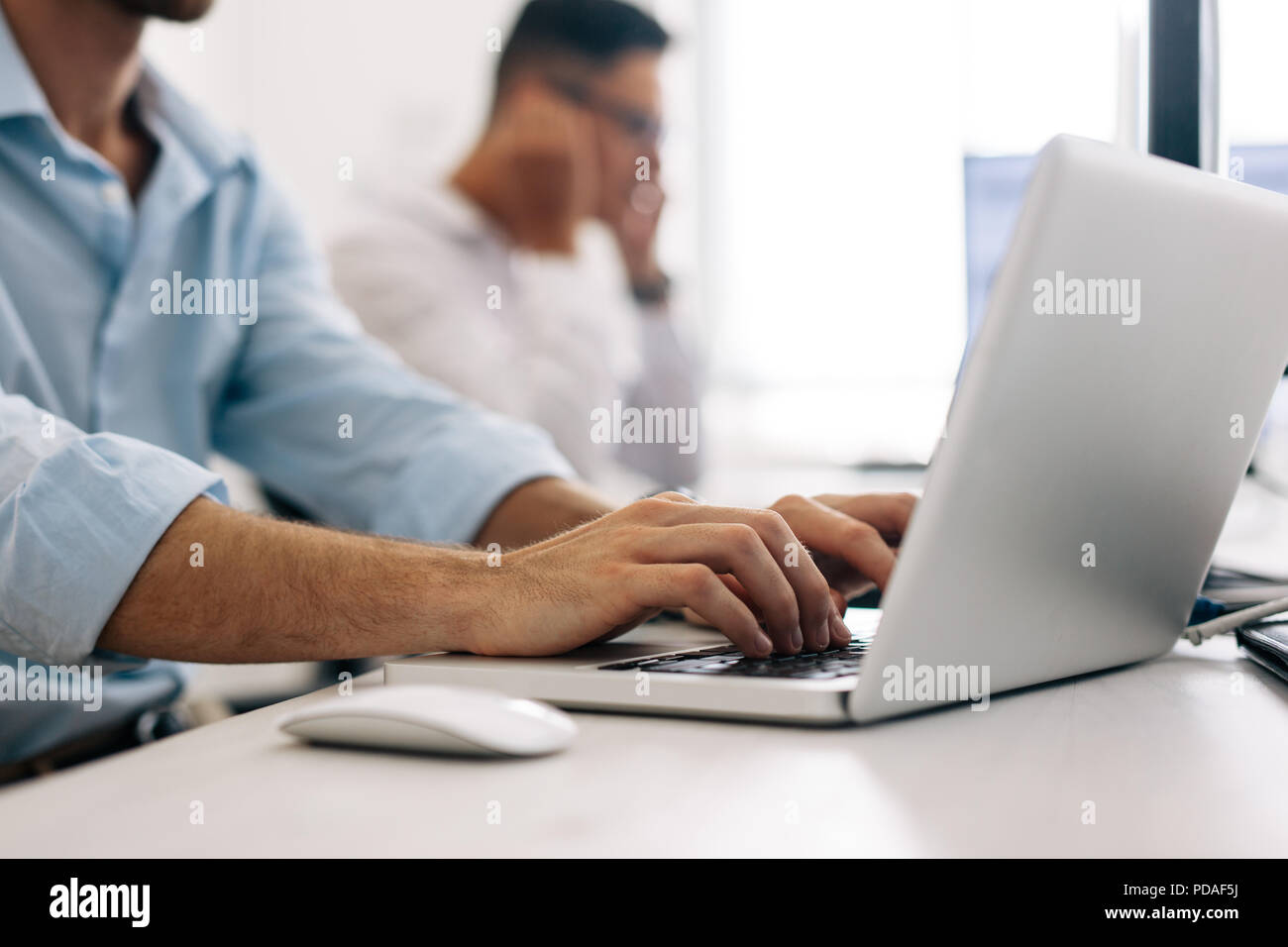 Software developers at office working on computers. Close up of an application developer working on a laptop in office. Stock Photo