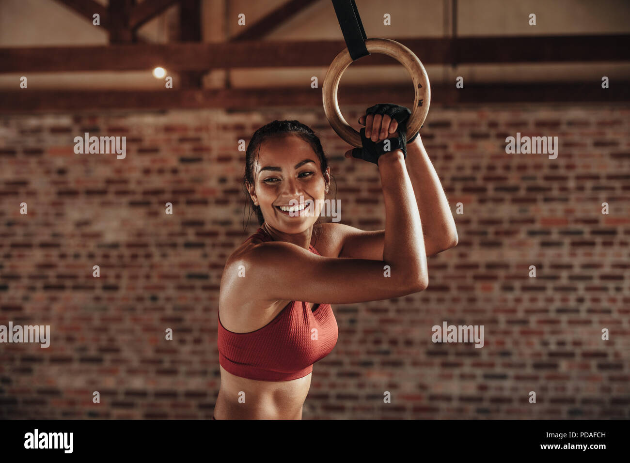 Sporty woman using gymnastic rings/ Sporty women in a gym exercising with gymnastic  rings Stock Photo
