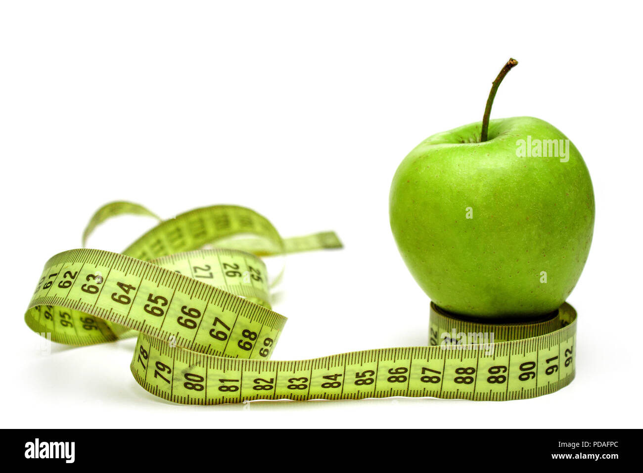 Diet, healthy eating, food and weigh loss concept. Measuring tape and green apple on white background Stock Photo