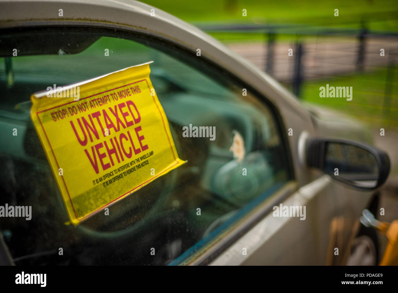 Detail Of A Warning Sign On The Window Of An Untaxed Vehicle With A Clamp On The Front Wheel Stock Photo