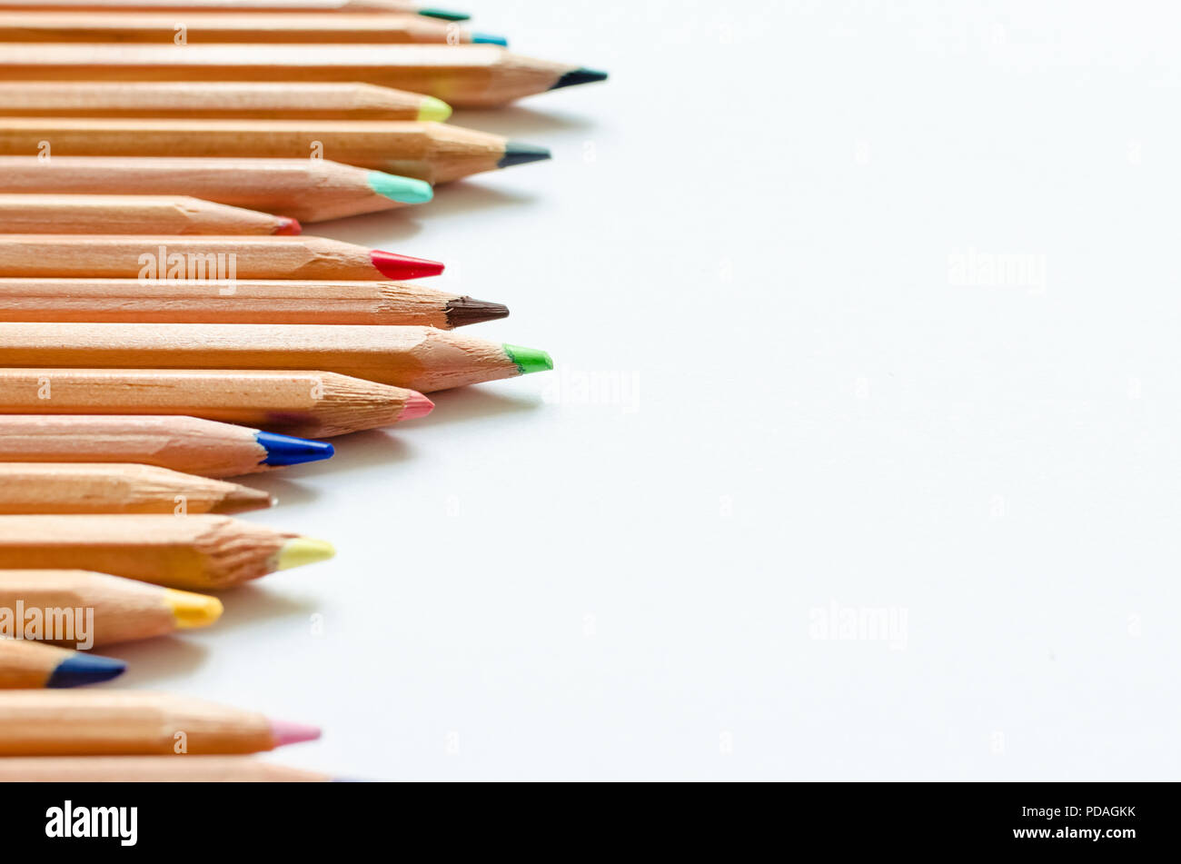 Wooden color pencils on empty white paper. Minimalist template with copy space close up macro. Stock Photo