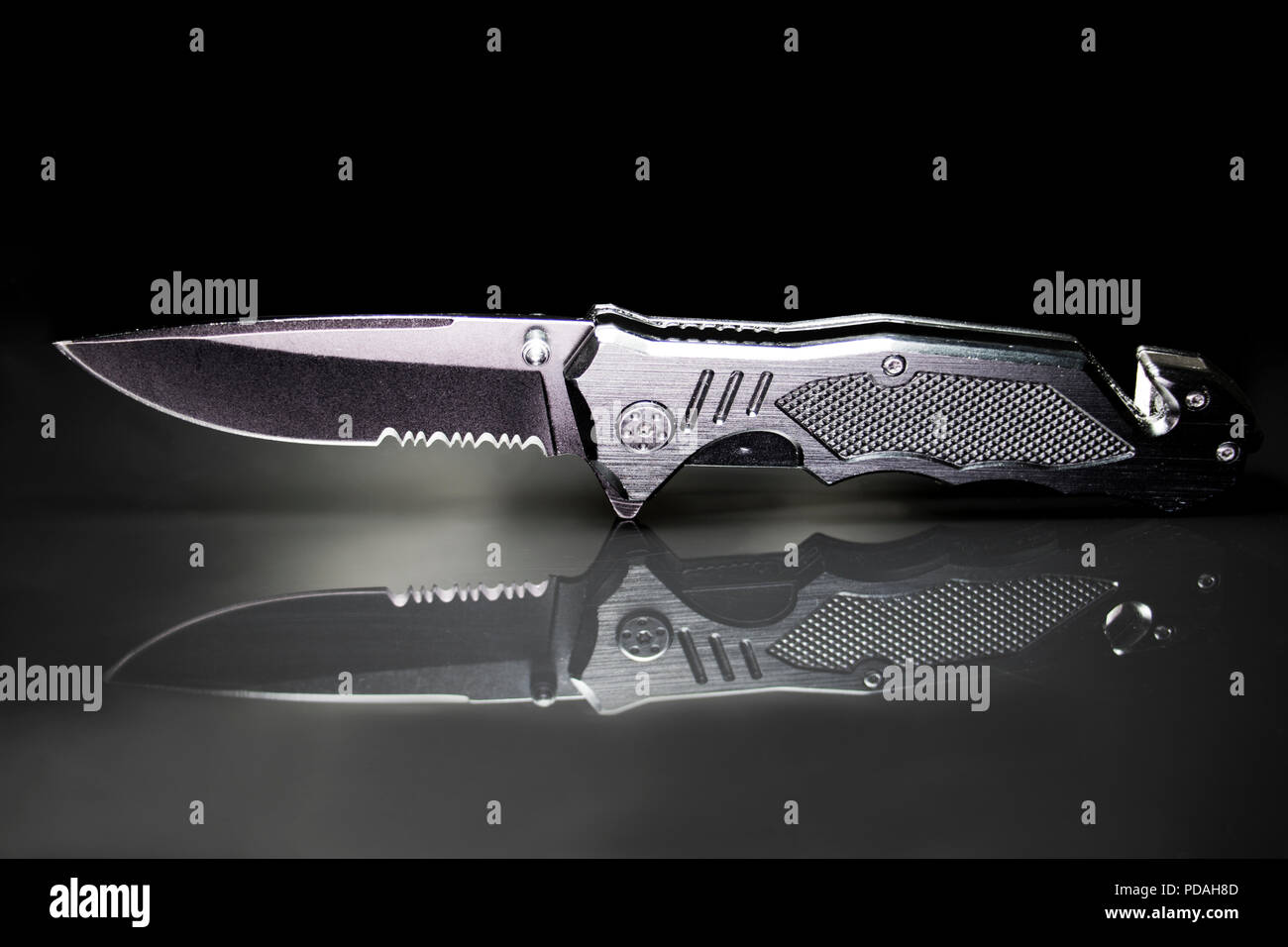 Black tactical knife reflecting on glass. Macro of an army knife with a