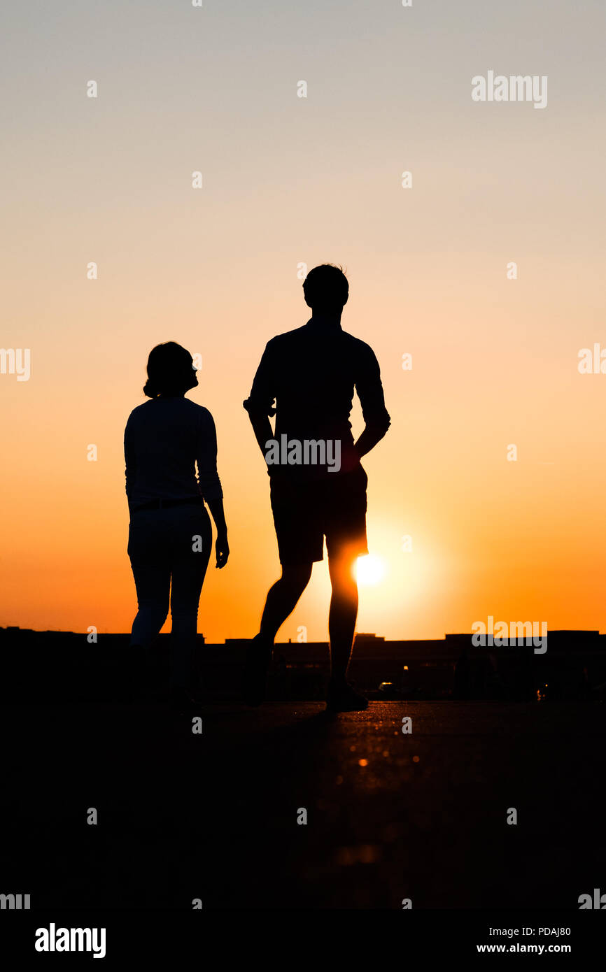 silhouette of boy and girl on sunset sky background Stock Photo