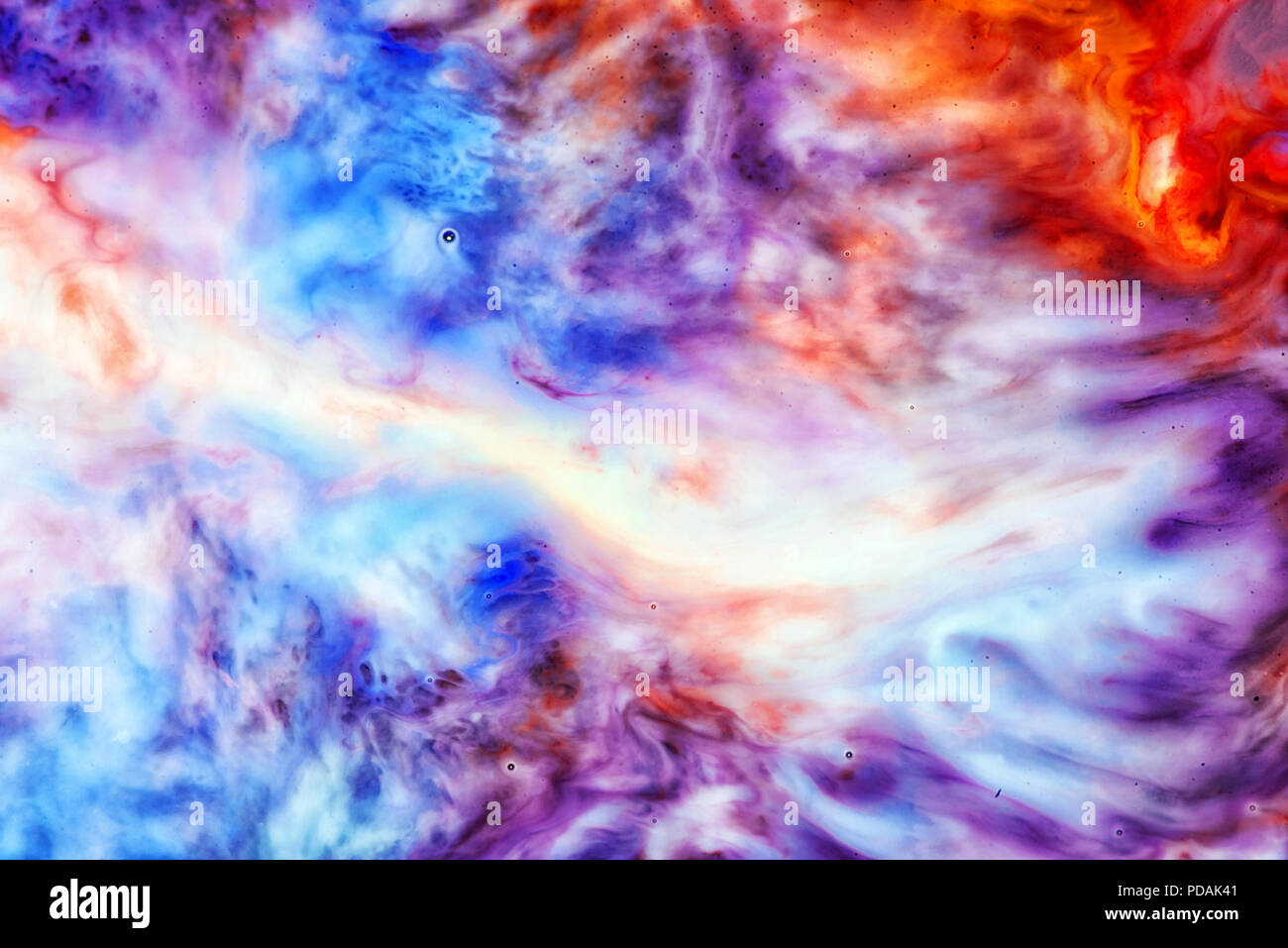 Abstract liquid milk flowing pattern like nebulae in the universe with different colours of white, blue, red and pink Stock Photo