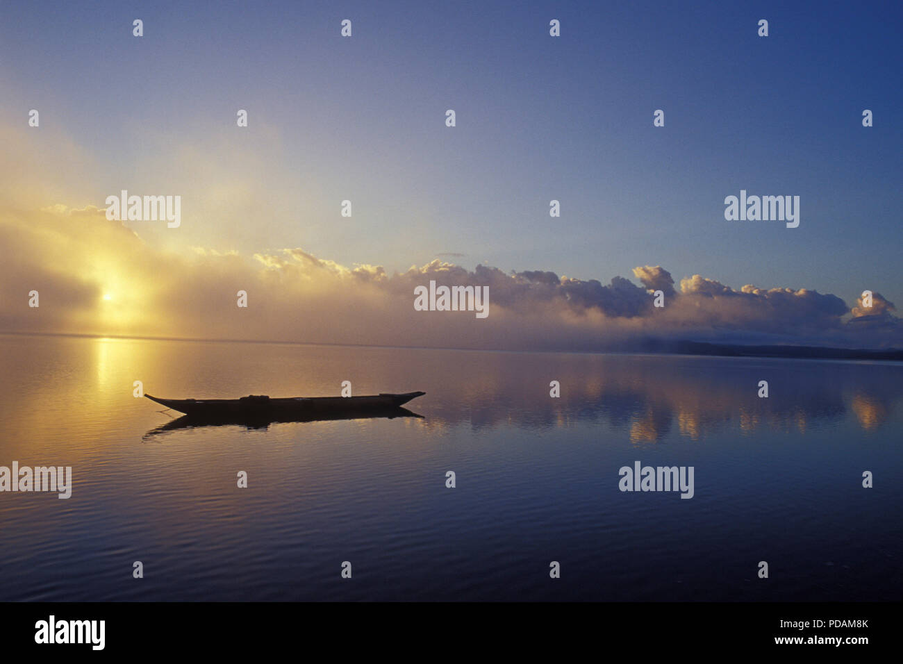 Fishing boat, silhouette of canoe in sunrise, quiet sea landscape, morning mist dissipating. Bahia State, Brazil. Stock Photo