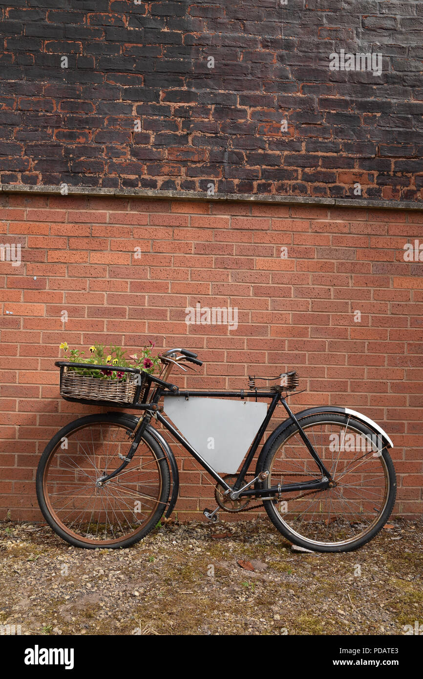 Rusty vintage bicycle leaning against a red brick wall hires stock