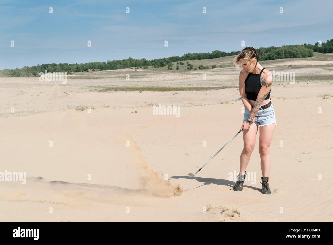 Woman is hitting with a golf club Stock Photo