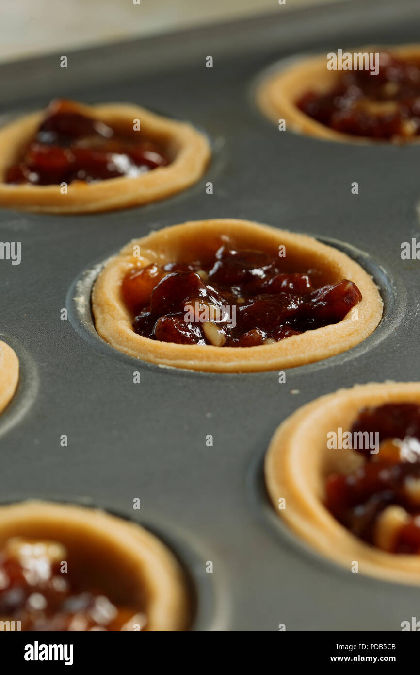 Mince pies with filling in a metal baking tray ready for topping Stock