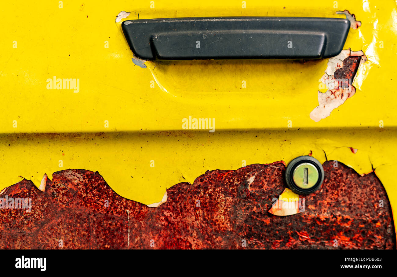 Close up old car door with rusty. Abandoned rusty yellow car with black handle. Car coloring is