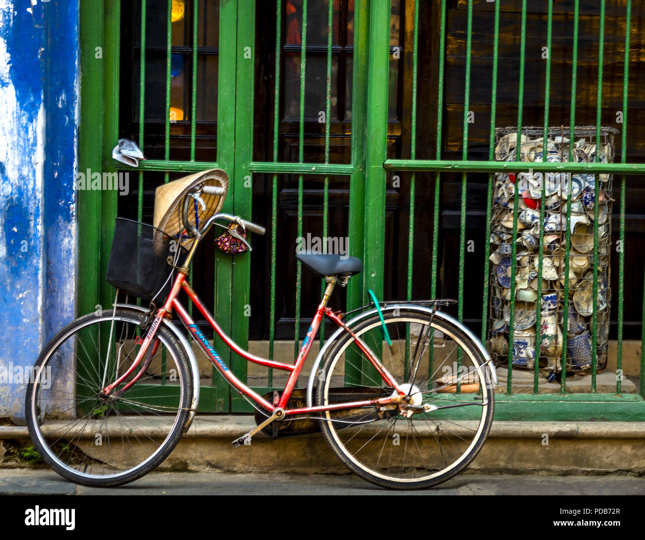 Parked bicyle in the Old City Hoi An along a wall and and a green bar section. Stock Photo