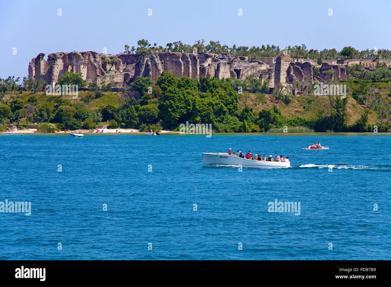 Excursion boat at Grotto of Catullus, above ruins of ancient roman villas, Sirmione, Lake Garda, Lombardy, Italy Stock Photo