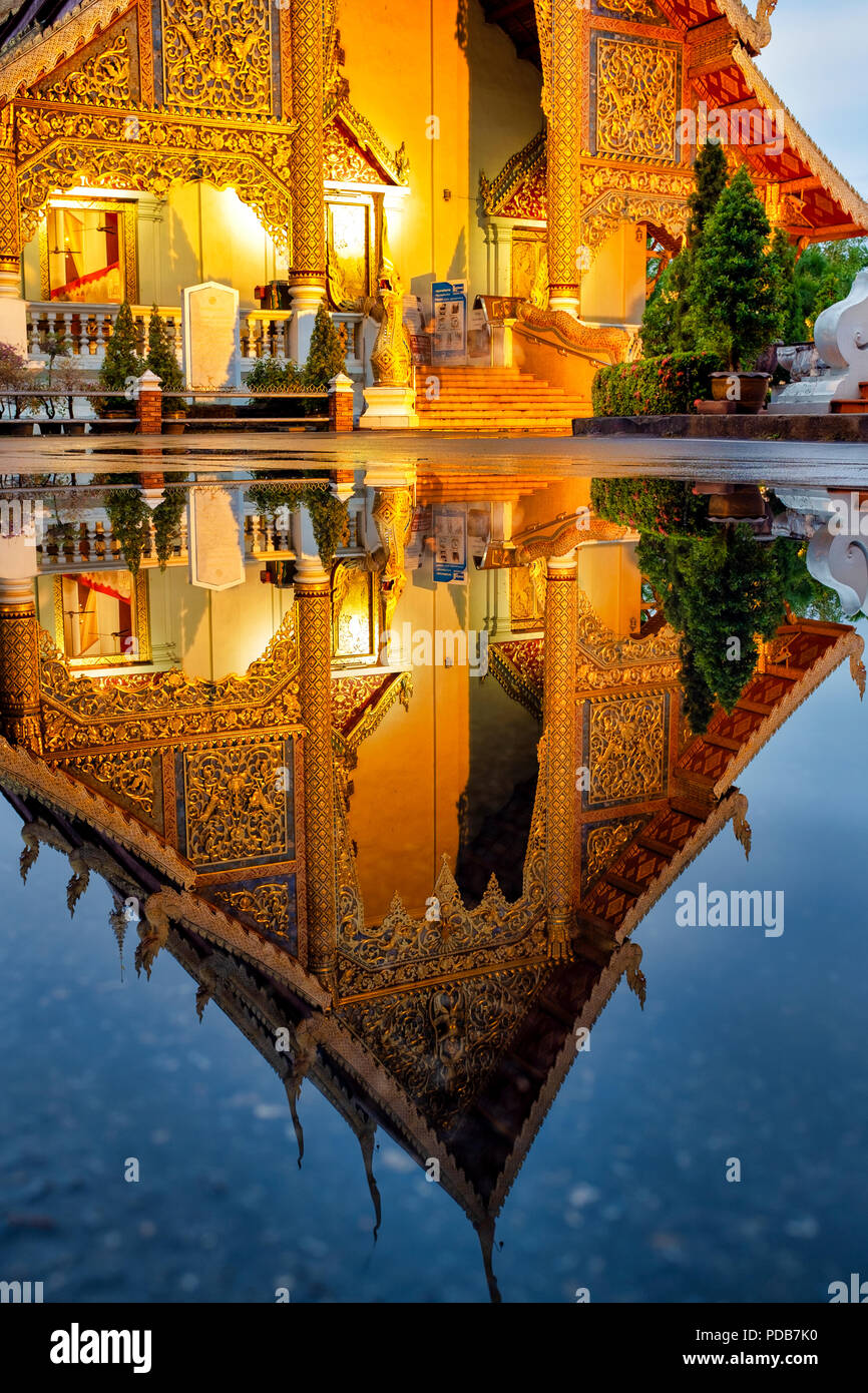 Reflection of the Wihan Luang of Wat Phra Singh in the water of a puddle, Chiang Mai, Thailand Stock Photo