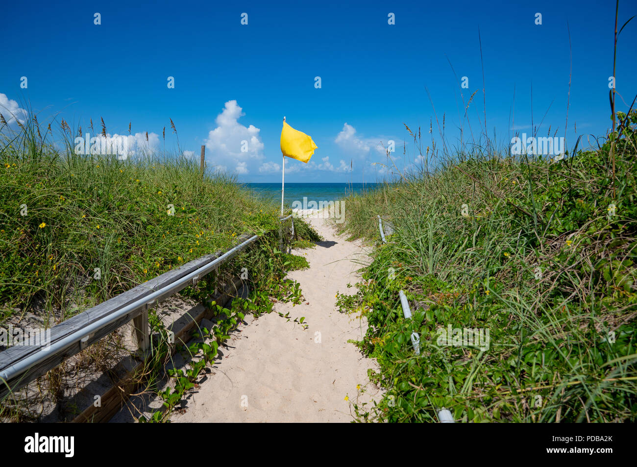 A Yellow Flag at the entrance to the beach warns of dangerous rip currents Stock Photo