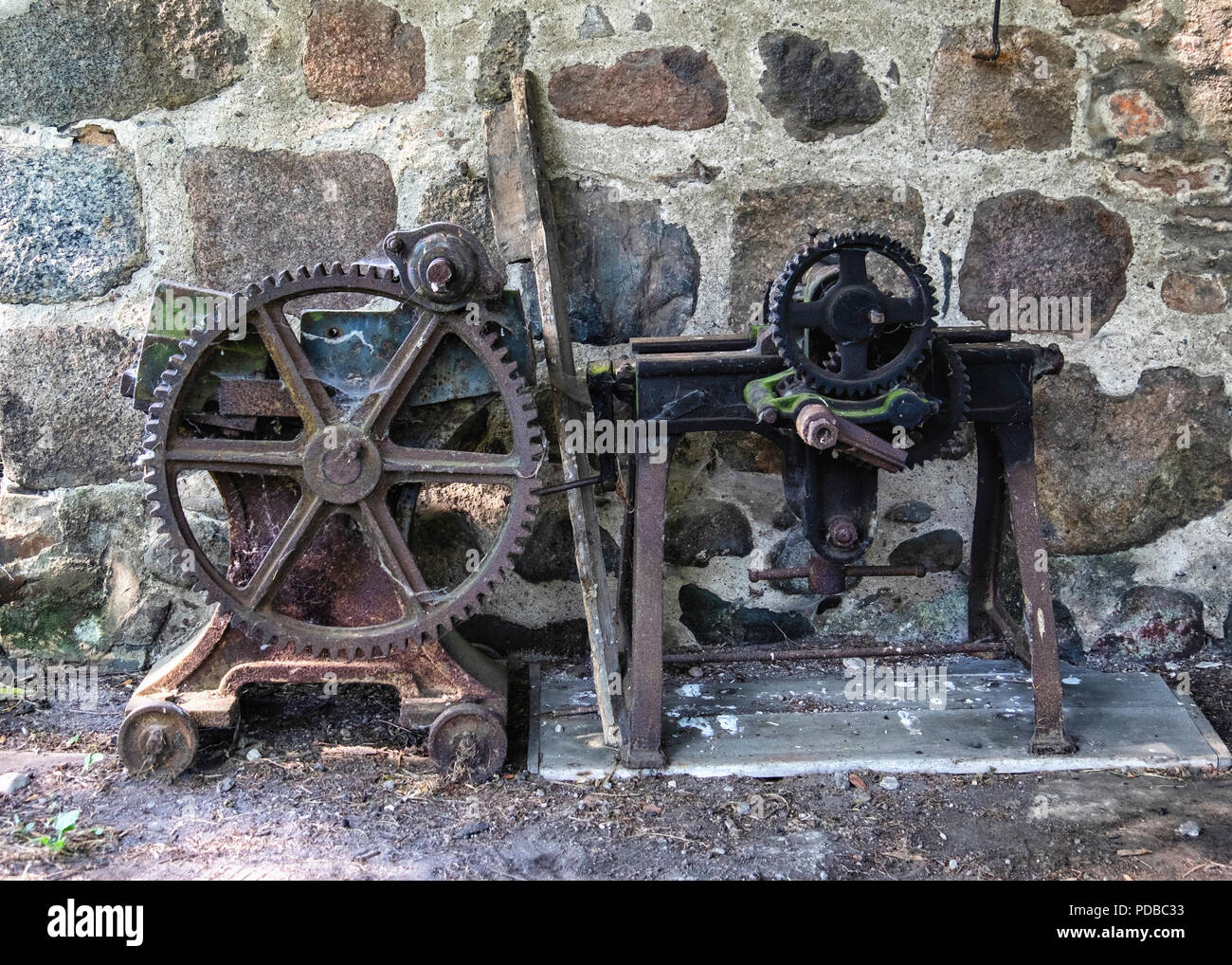 Germany,Stolpe an der Peene, Historic old blacksmith on Gutshaus Stolpe Estate grounds. Rusty machinery & stone wall                                   Stock Photo