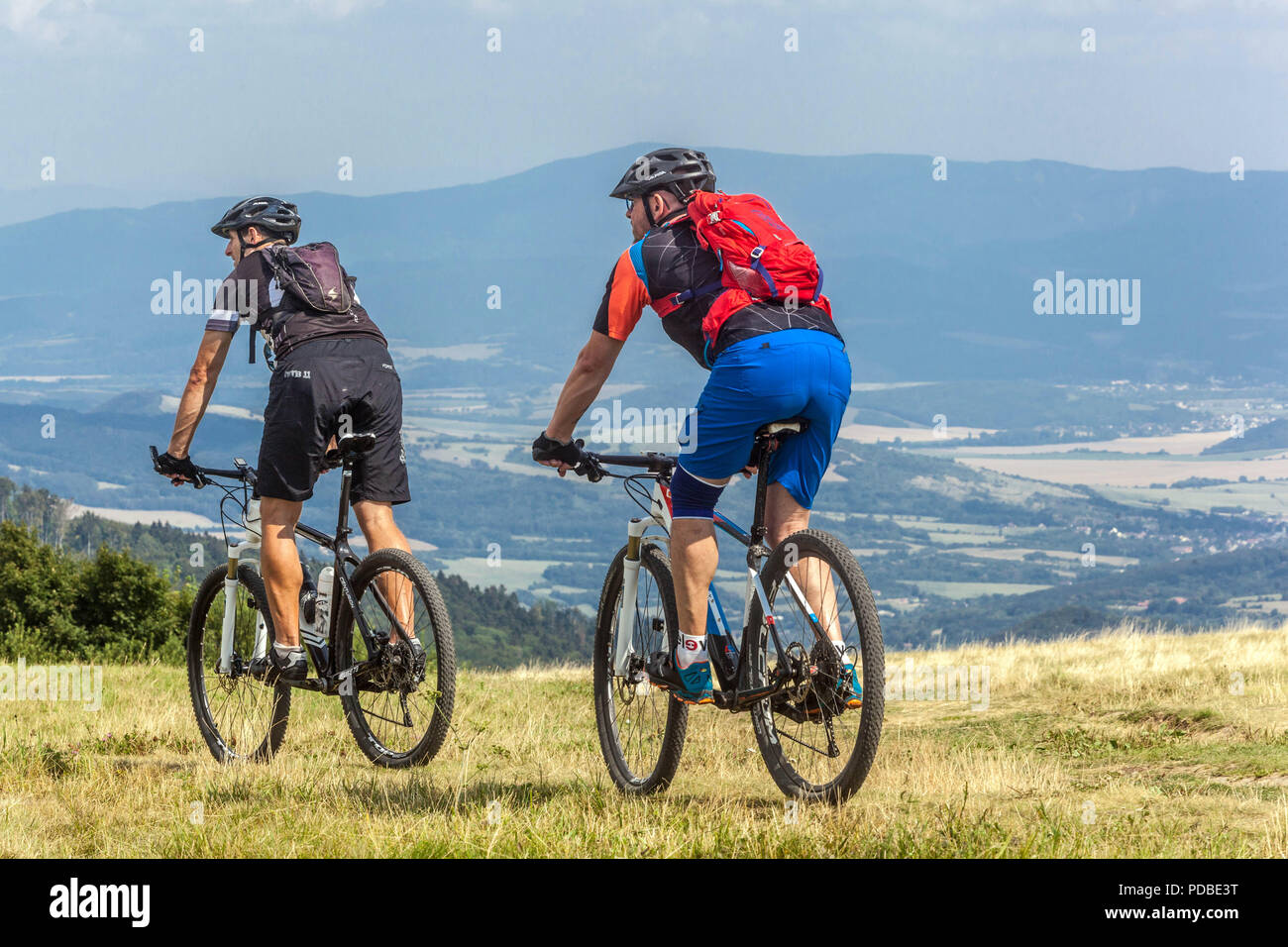 Bikers cycling on a mountain trail Men riding a bike Velka Javorina hill Czech Slovak border in White Carpathians people cycling countryside on a hill Stock Photo
