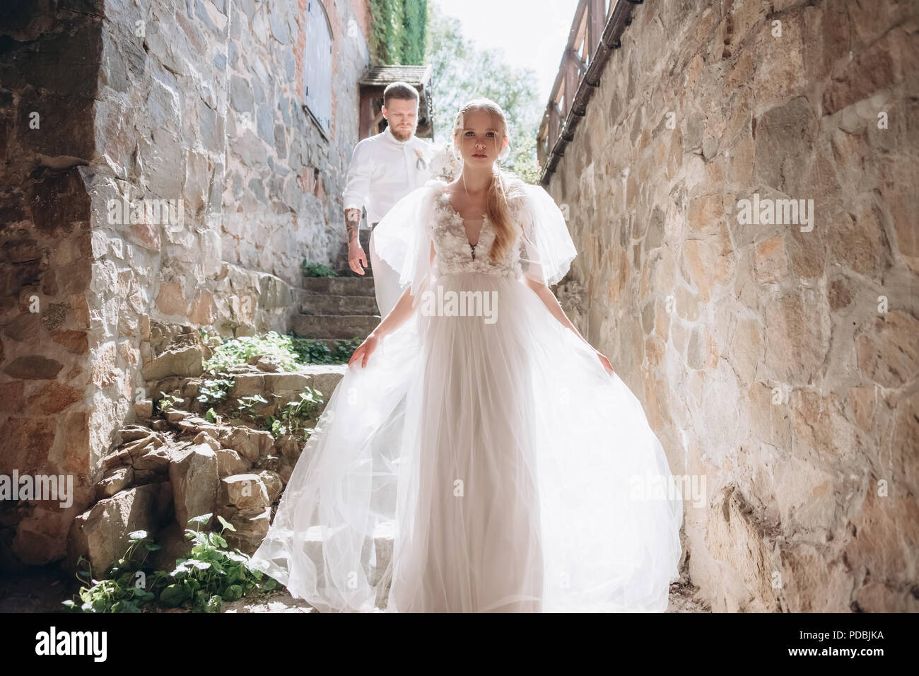 beautiful bride and groom on stairs of ancient building in old town ...