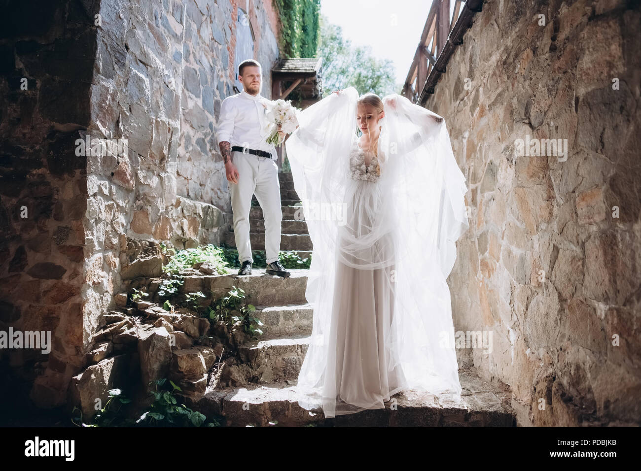 beautiful bride and handsome groom on stairs of ancient building in old ...