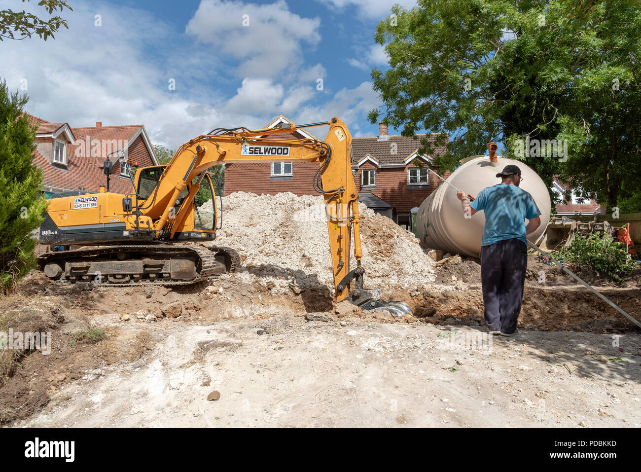 A excuvator crawler digging a trench for an underground tank on a housing development in Hampshire, England, UK Stock Photo