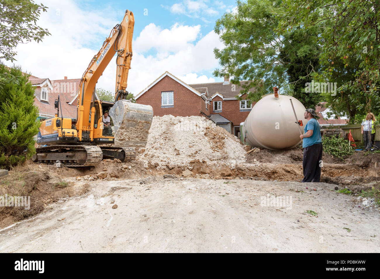 A Excuvator crawler digging a trench for an underground tank on a housing development in Hampshire, England, UK Stock Photo