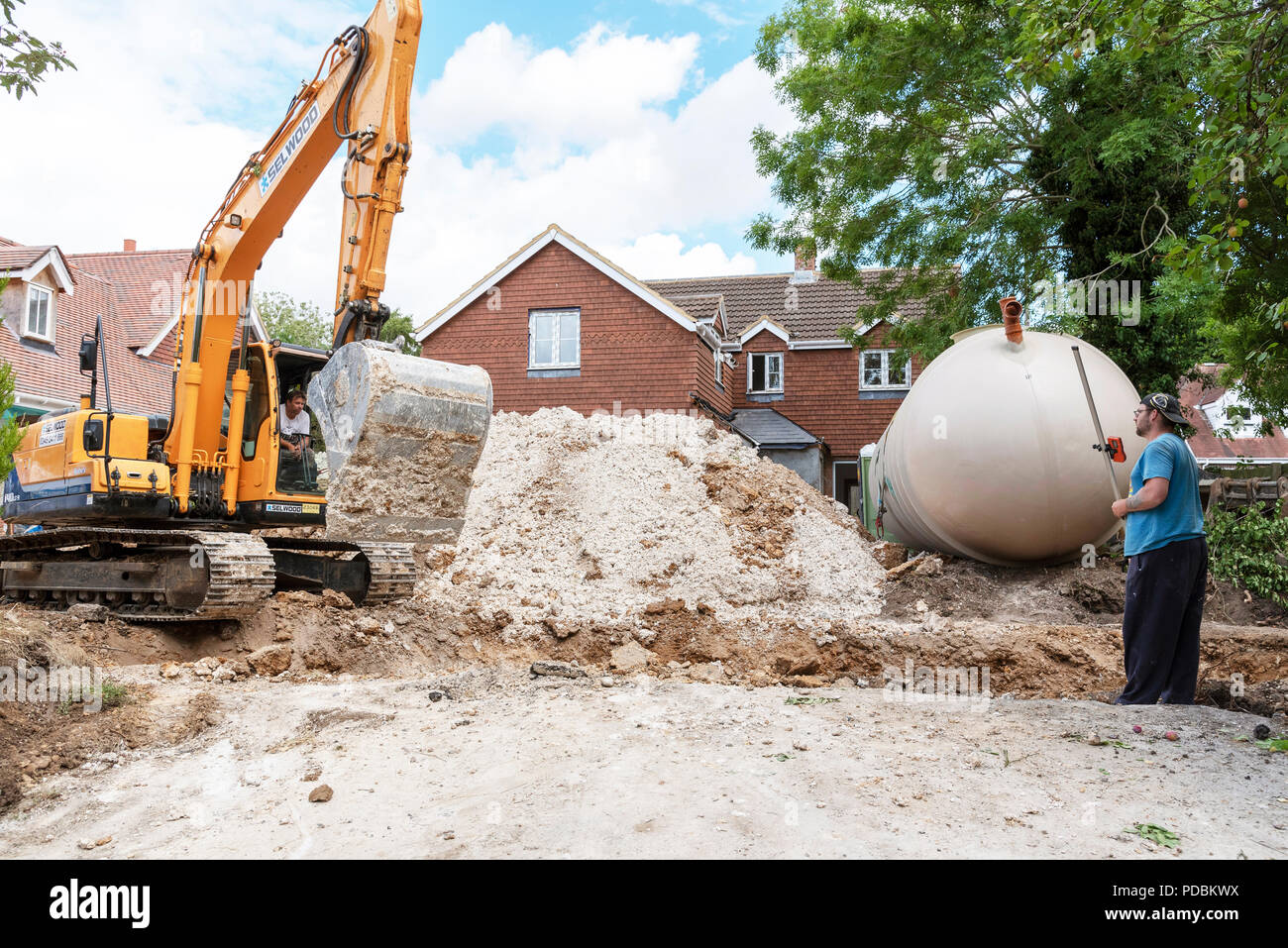 A Excuvator crawler digging a trench for an underground tank on a housing development in Hampshire, England, UK Stock Photo