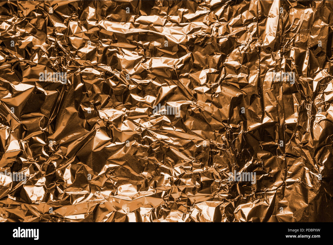 The close up of a coppery surface of aluminum foil. Metallic background. Stock Photo
