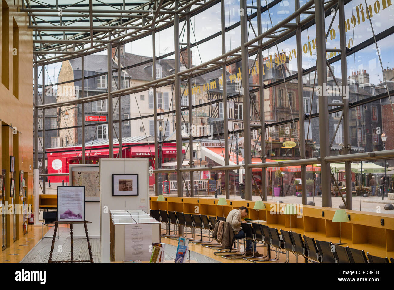 A view from the interior of the modern glass fronted public library in Honfleur, Normandy, France with the ancient buildings in the street outside Stock Photo