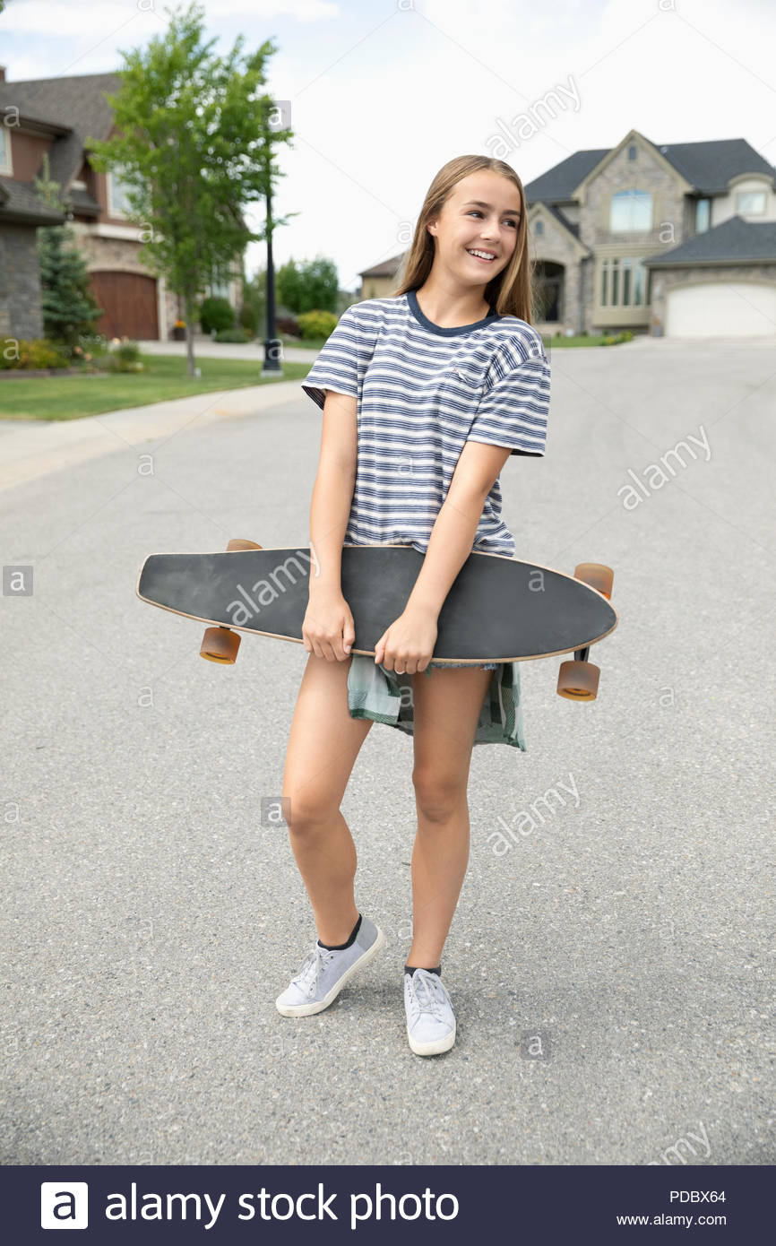 Tween girl with skateboard on neighborhood street Stock Photo
