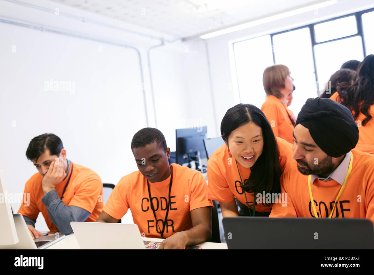 Hackers at laptops coding for charity at hackathon Stock Photo