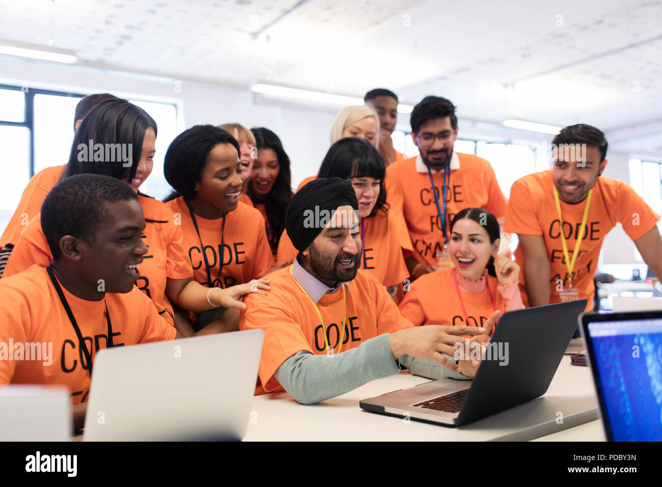 Happy hackers at laptop coding for charity at hackathon Stock Photo