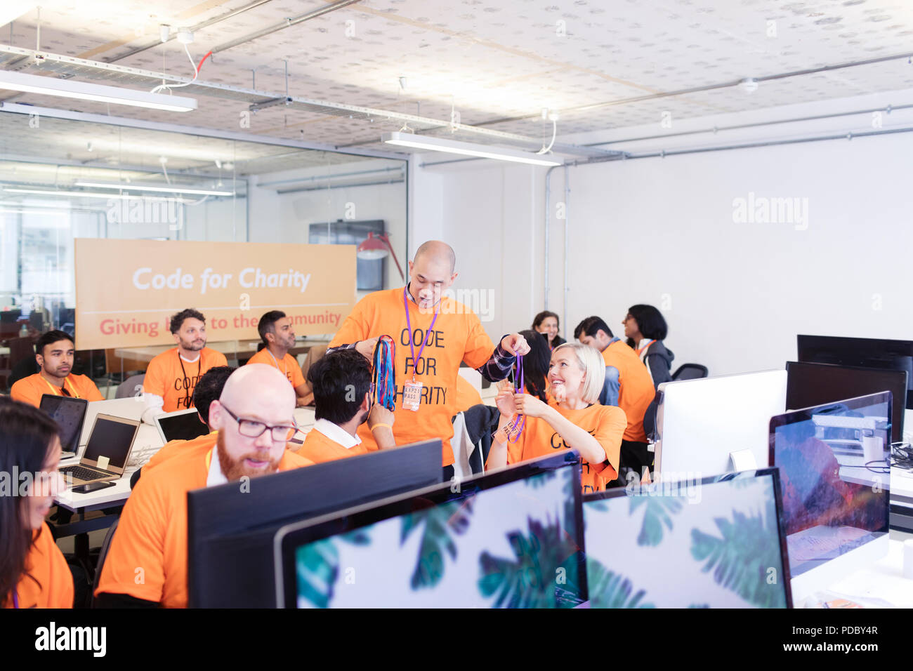 Hackers with lanyards coding for charity at hackathon Stock Photo