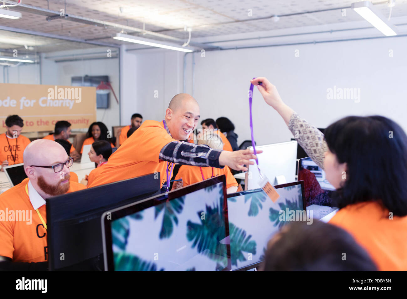 Hackers with lanyard, coding for charity at hackathon Stock Photo