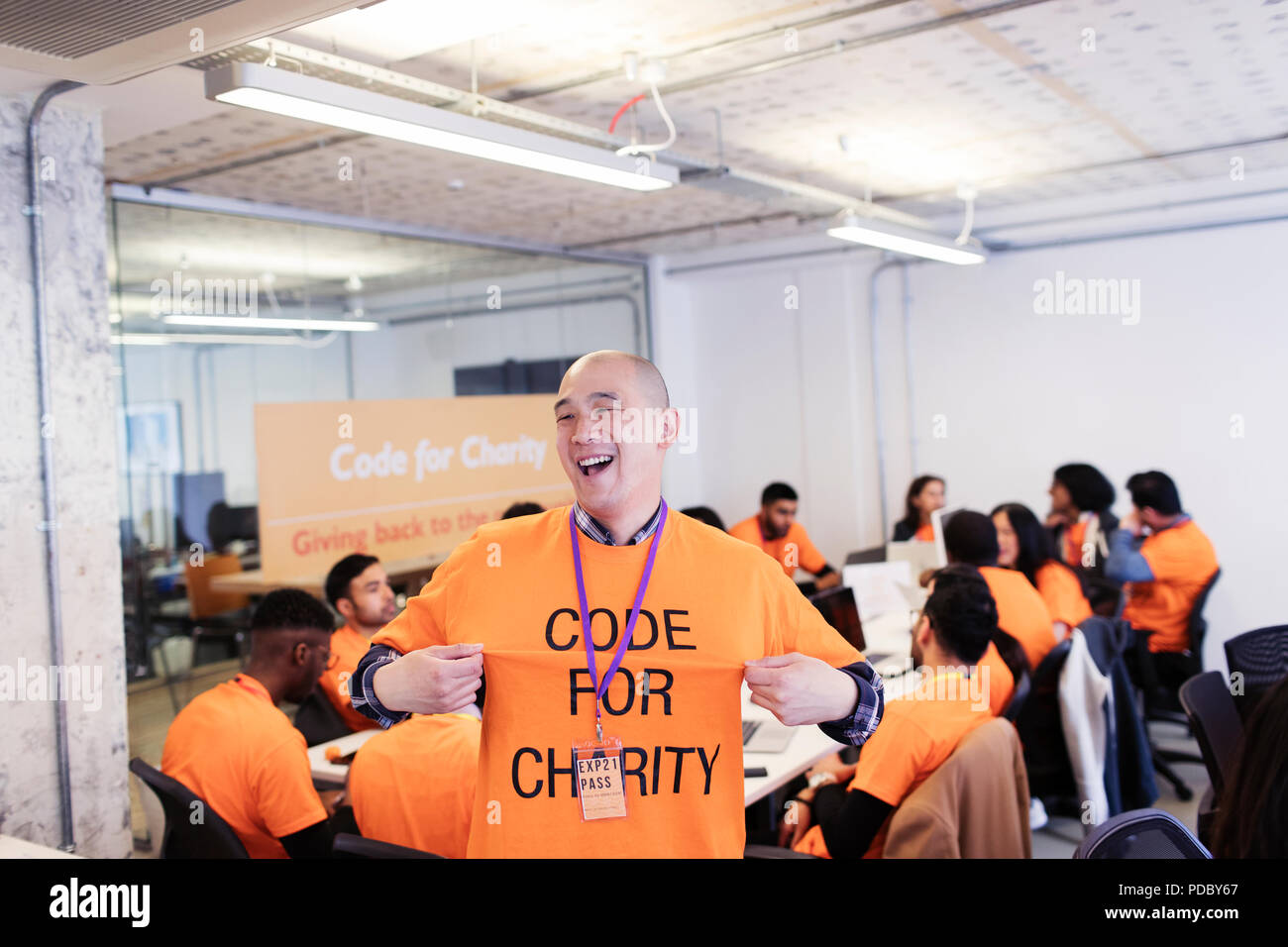 Playful hacker with t-shirt coding for charity at hackathon Stock Photo