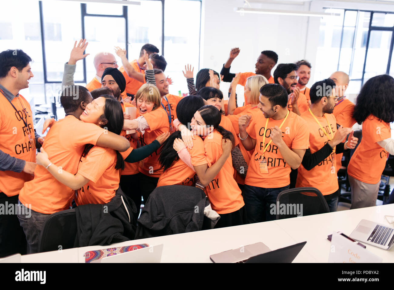 Enthusiastic hackers celebrating, coding for charity at hackathon Stock Photo