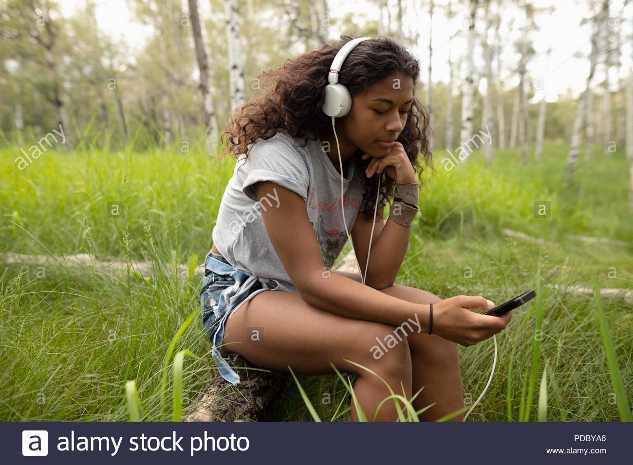 Young woman with headphones listening to music with mp3 player in woods Stock Photo