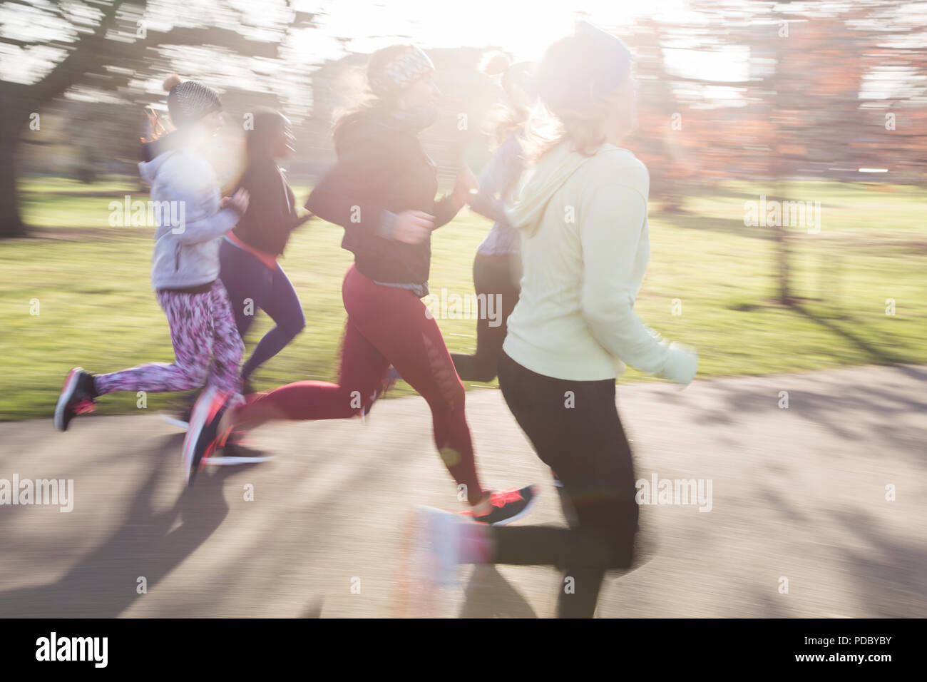 Female runners running in sunny park Stock Photo