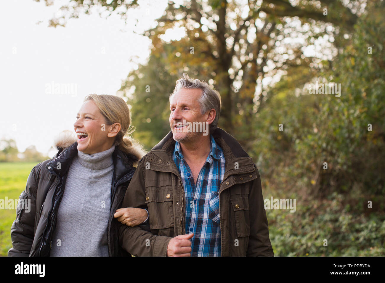 Happy mature couple walking arm in arm in autumn park Stock Photo