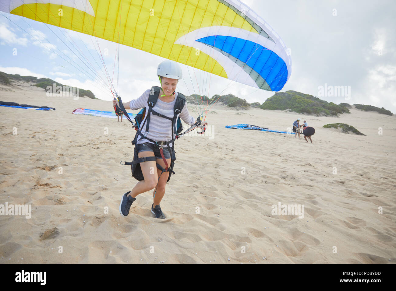 Female paraglider with parachute running, taking off on beach Stock Photo