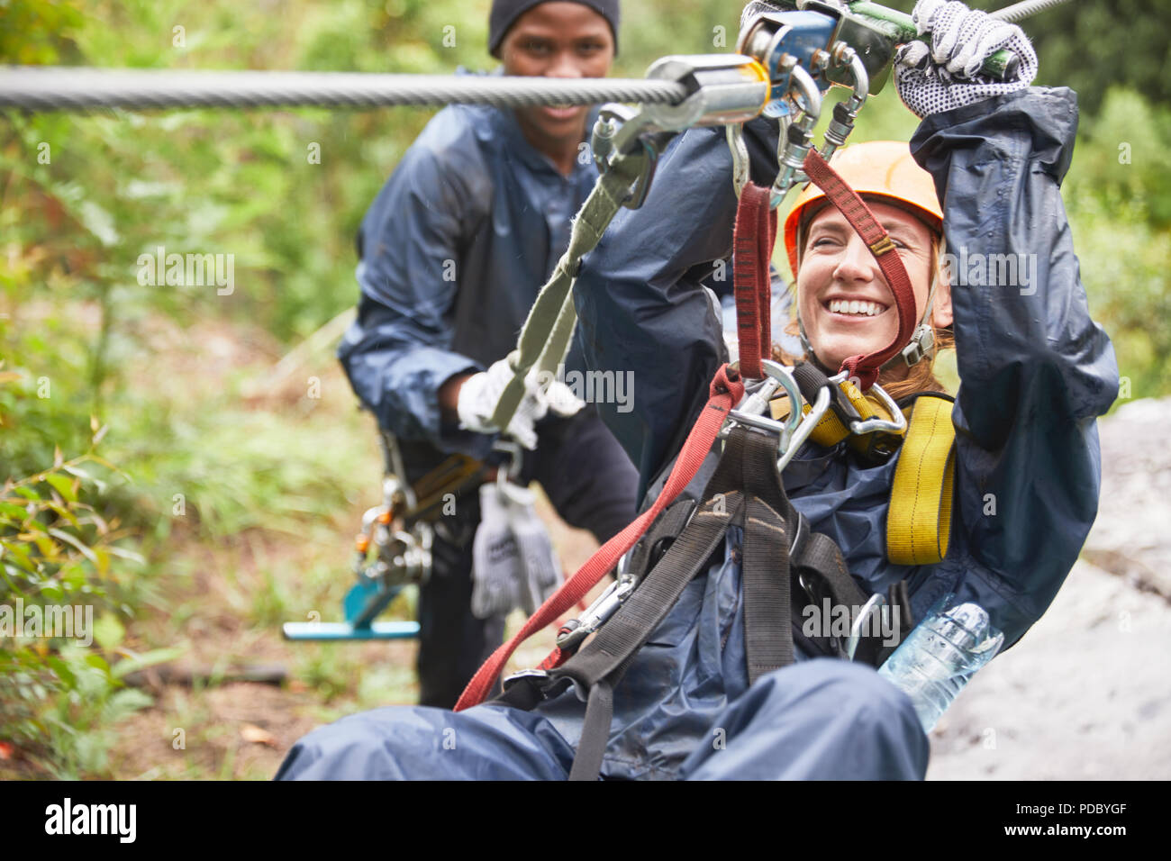 Smiling young woman zip lining Stock Photo