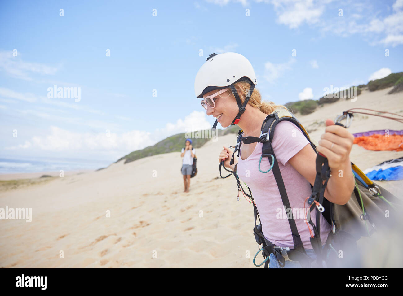 Smiling female paraglider with equipment on beach Stock Photo