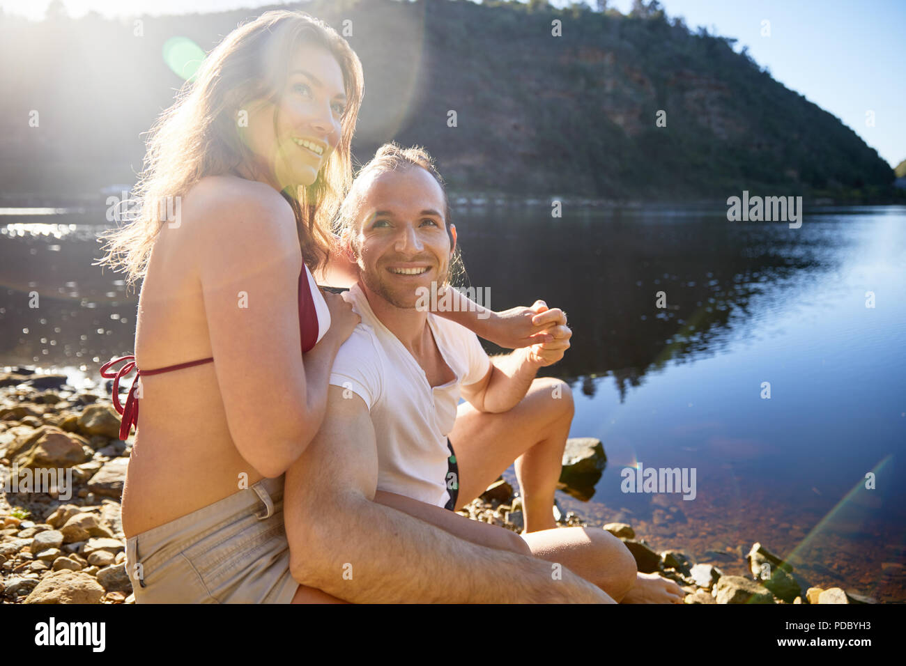 Portrait affectionate, carefree couple holding hands at sunny summer lake Stock Photo