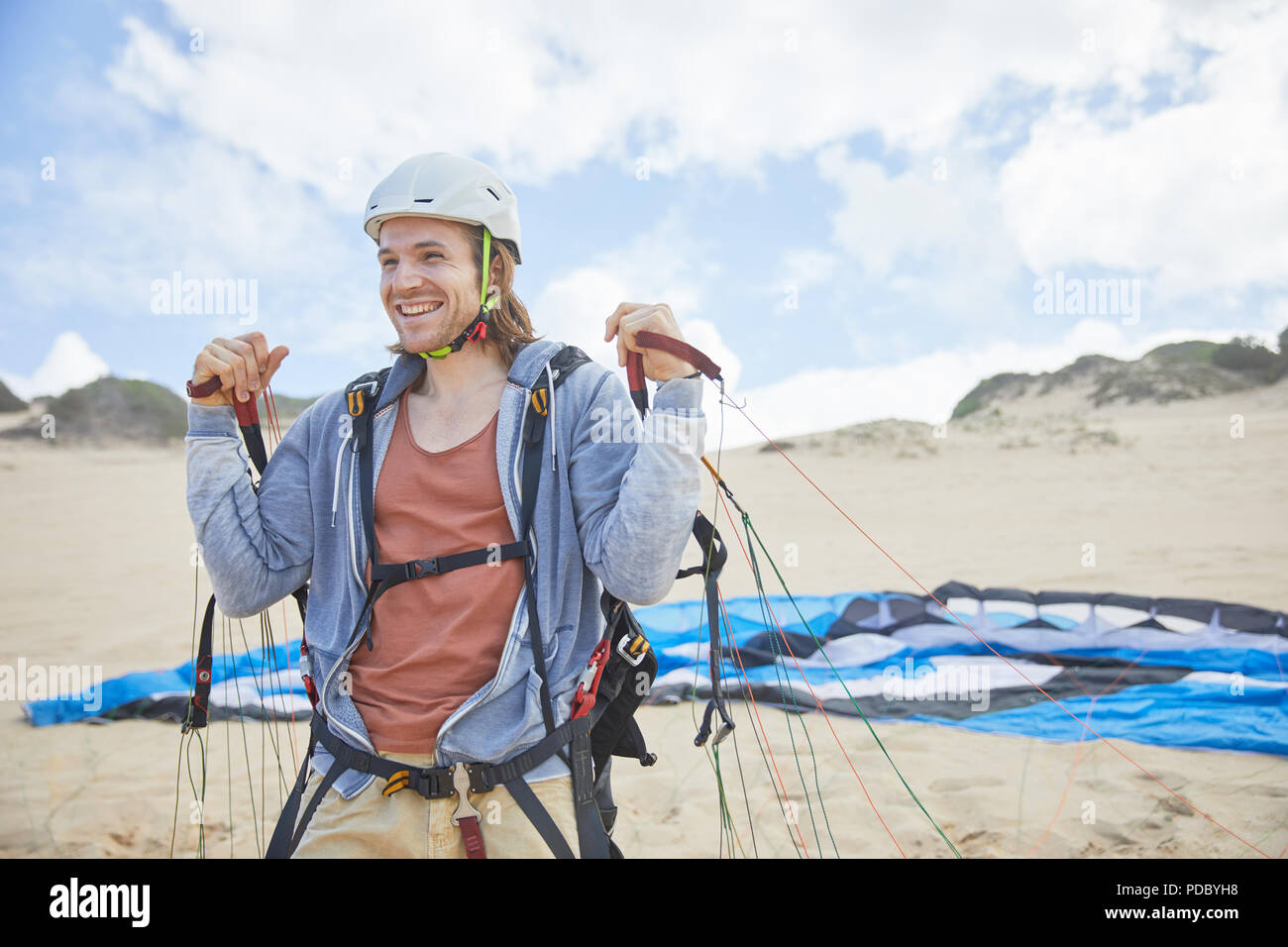 Smiling, confident paraglider with parachute on beach Stock Photo