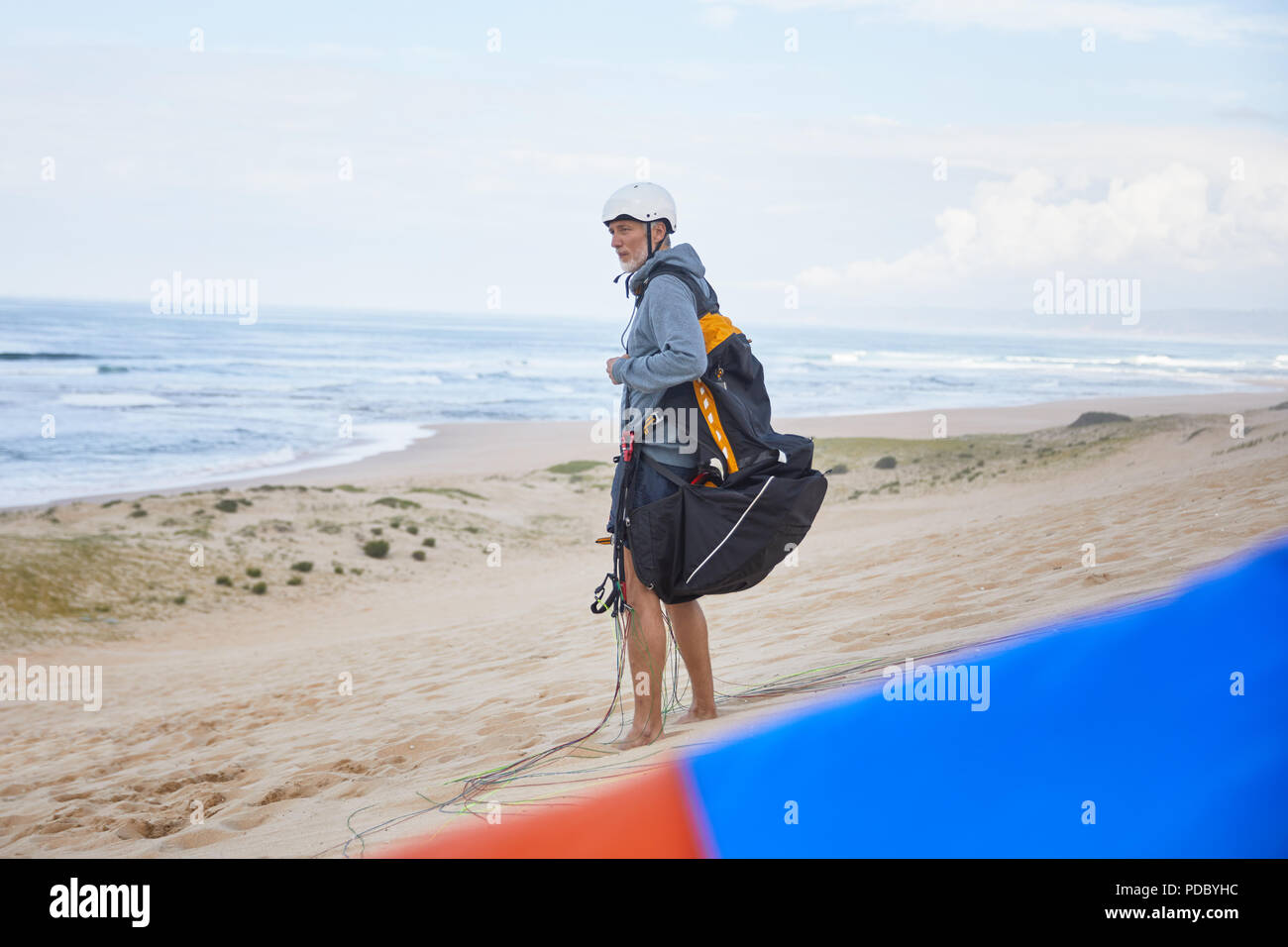 Paraglider with parachute backpack on ocean beach Stock Photo