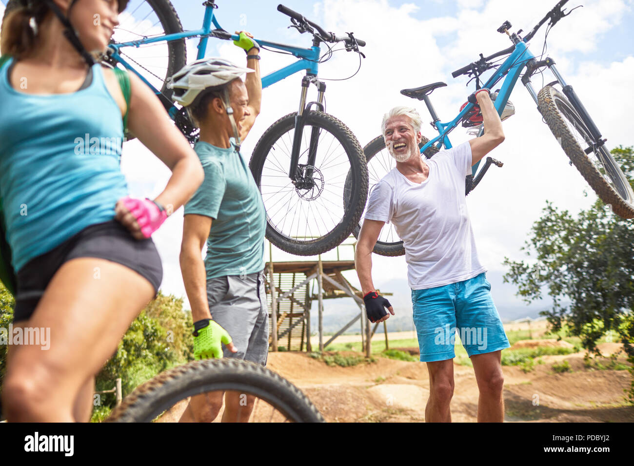 Carefree friends carrying mountain bikes Stock Photo